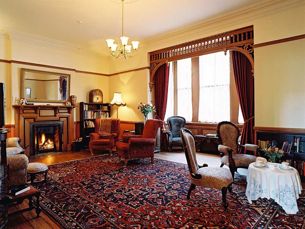 The guest lounge at Braemar on Parliament Street with an open fireplace and Victorian detailing