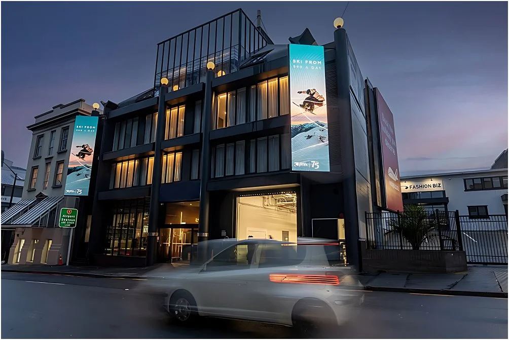 The Viv Hotel in Wellington lit up at dusk, with its dark facade and street-level entrance