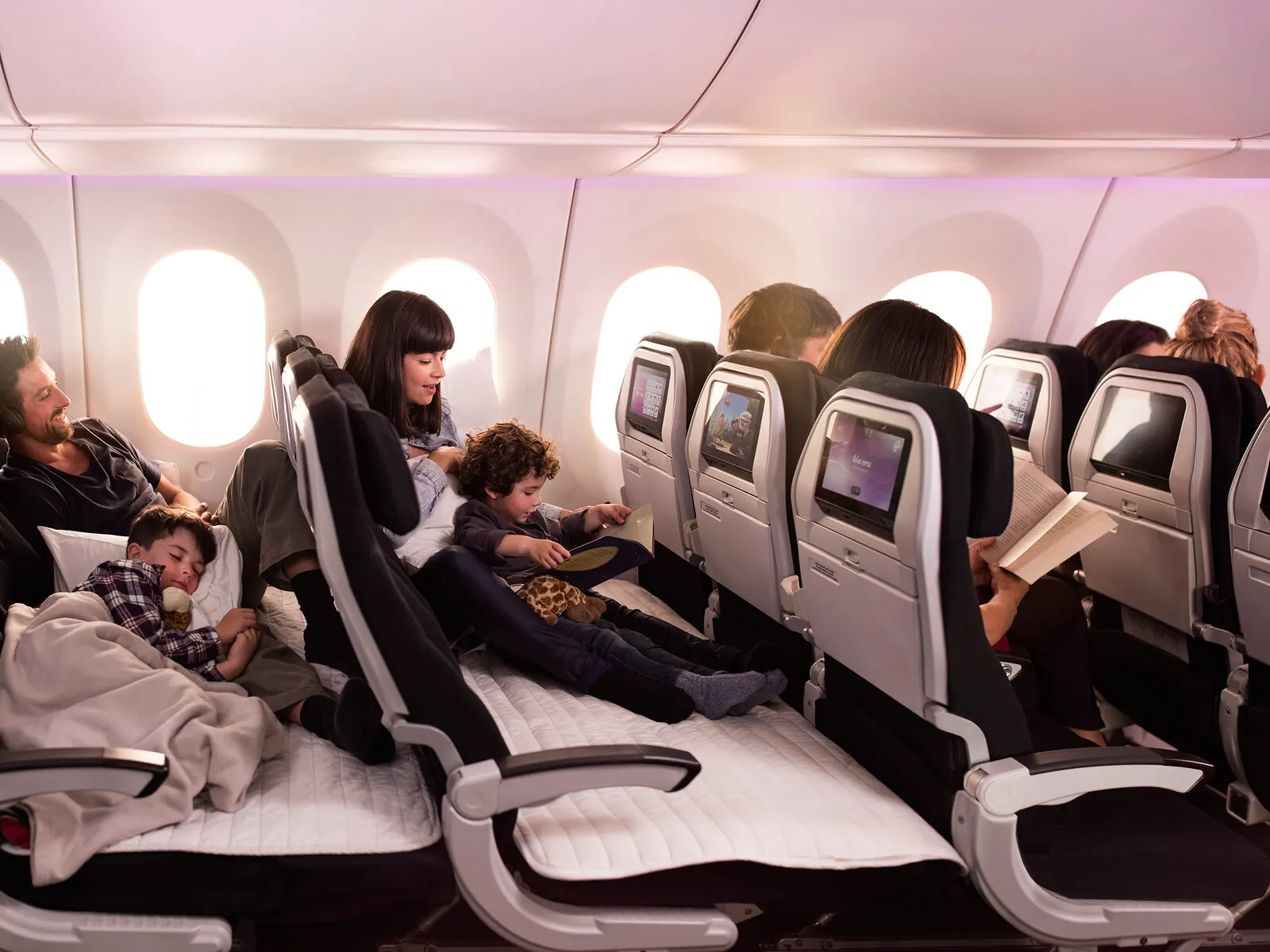 A family on the Air New Zealand Economy Skycouch, leg rests raised to form a flat couch